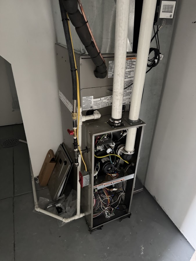 Furnace in a utility closet with white vent pipes
